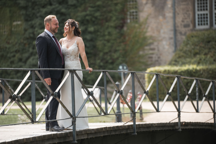 Brautpaar posiert nach der Hochzeit auf der Brücke am Schloss Wolfsburg